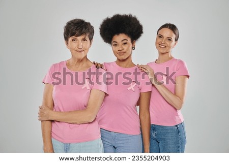 breast cancer awareness, happy multicultural women smiling on grey backdrop, different generations Royalty-Free Stock Photo #2355204903
