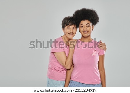 breast cancer awareness, happy multicultural women hugging on grey backdrop, support campaign Royalty-Free Stock Photo #2355204919
