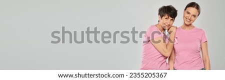 breast cancer awareness concept, two women with pink ribbons on grey backdrop, cancer free, banner Royalty-Free Stock Photo #2355205367
