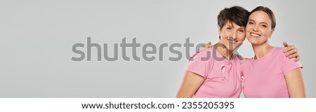 breast cancer concept, happy women looking at camera and hugging on grey backdrop, support, banner Royalty-Free Stock Photo #2355205395
