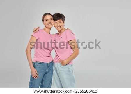 breast cancer concept, happy two women looking at camera, hug and smile, grey backdrop, support Royalty-Free Stock Photo #2355205413
