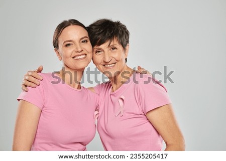 breast cancer concept, happy two women looking at camera and hugging on grey backdrop, support Royalty-Free Stock Photo #2355205417