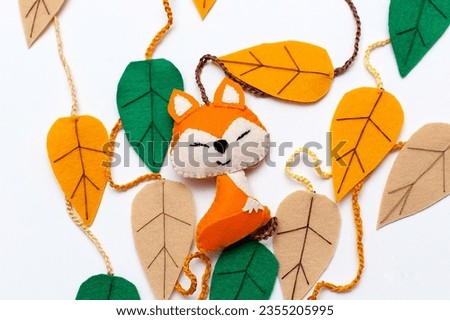 Orange fox on blue wooden boards with multicolored autumn leaves from fabric. Textile handmade fabric doll toy.