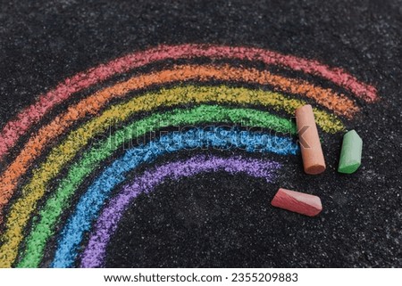 Close-up of a colorful rainbow painted on a road with sidewalk chalk, shot from above
