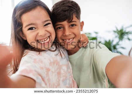 Hispanic little siblings taking a selfie at home - preschool girl and elementary school boy happy siblings social media Royalty-Free Stock Photo #2355212075