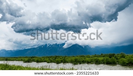 Cumulonimbus clouds sky with strong rain, big mountains and wild tirkiz river.High resolution.