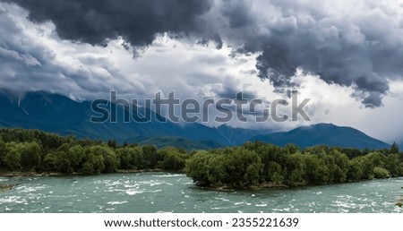 Cumulonimbus clouds sky with strong rain, big mountains and wild tirkiz river.High resolution.