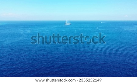 An aerial shot of a yacht sailing across the deep blue ocean with the horizon in the distance