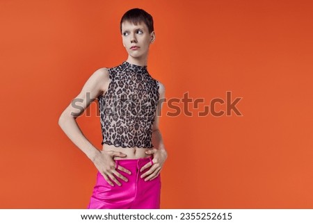fashion concept, queer, young man posing on orange backdrop, animal print, leopard print, stylish
