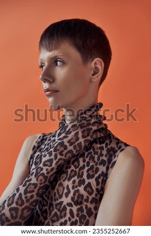 queer person, fashion concept, young man posing on orange backdrop, animal print, leopard print