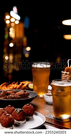 happy hour feast with finger food portions on a table set with dishes such as starters, beers, wines, drinks Royalty-Free Stock Photo #2355260201