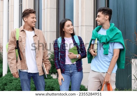 Happy young students spending time together outdoors