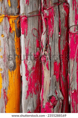 wooden fence posts close together painted yellow and red with paint peeling allowing wood grain showing underneath  layer of paint vertical image room for type colorful background backdrop  wallpaper Royalty-Free Stock Photo #2355288169