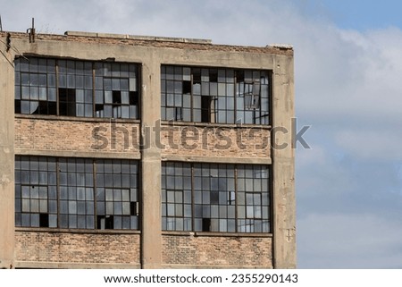 Abandoned automotive factory with broken windows. Abandoned factories are dangerous and eyesores for the community. Royalty-Free Stock Photo #2355290143