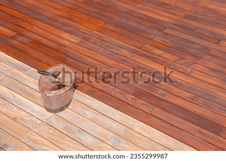 Wood deck oil and paint brush on the bucket, exterior terrace renovation treatment and maintenance Royalty-Free Stock Photo #2355299987