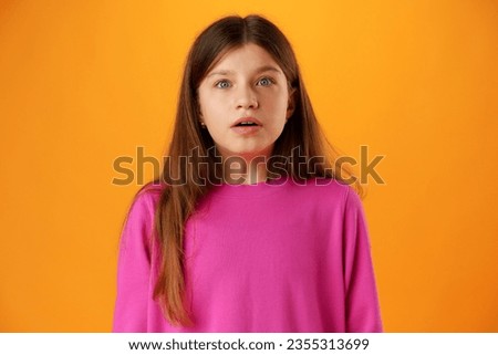 Anxious teen girl looking scared or worried on yellow background Royalty-Free Stock Photo #2355313699