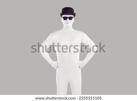 Portrait of faceless unrecognizable person wearing black hat and glasses in white spandex costume. Incognito man in bodysuit lokking confidently at the camera in studio isolated on grey background. Royalty-Free Stock Photo #2355315105