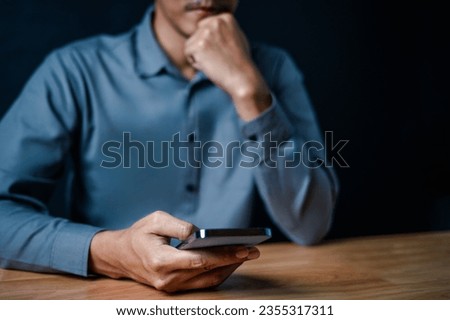 smart phone, close up, people, hand, businessman, portrait, showing, background, blue, equipment. picture is portrait close up to businessman, him hold smart phone, look fixedly at, in a serious way.