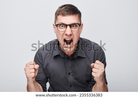 Portrait of angry young man yelling clenching fists isolated on white studio background. Devil face. Human emotions, facial expression football fan concept Royalty-Free Stock Photo #2355336383