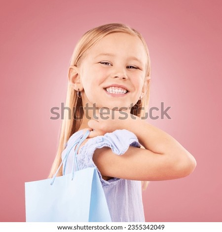 Portrait, girl kid with shopping bag or gift, customer and purchase with fashion or birthday party on pink background. Retail, smile and child with present, luxury and event with happiness in studio