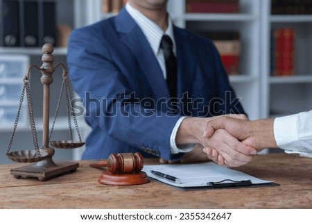 The lawyer sitting at desk with scales of justice, gavel and small wooden house, working with documents, signing contract agreements. Real estate law, foreclosed property, lawyer services concept