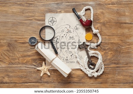 Treasure map with magnifier, scroll and smoking pipe on brown wooden background