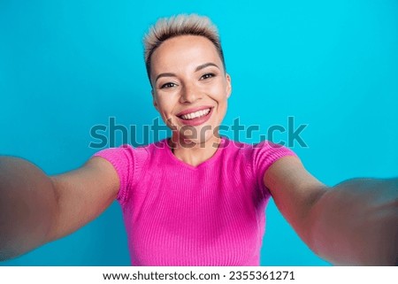 Photo of gorgeous good mood girl with short haircut dressed pink t-shirt hold camera doing selfie isolated on blue color background Royalty-Free Stock Photo #2355361271