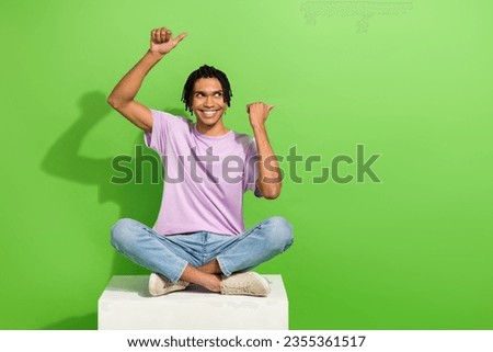 Photo of funky dreamy man dressed purple t-shirt pointing two thumbs looking empty space isolated green color background