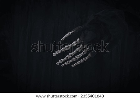 Skeleton zombie hand on blurred black background for Halloween night. Greeting Halloween invitation card, party