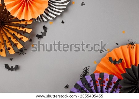Absorbing the eerie ambience of Halloween's arrival. Top view flat lay of paper fans, spooky insects on grey background with promo spot