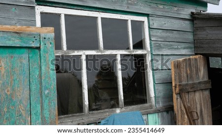 The window of a village house. An old wooden window in a house in the village next to the barn