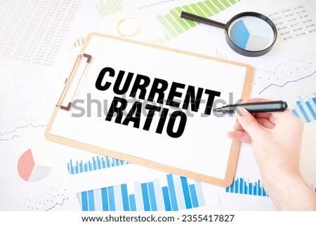 Text CURRENT RATIO on white paper sheet and marker on businessman hand on the diagram. Business concept Royalty-Free Stock Photo #2355417827