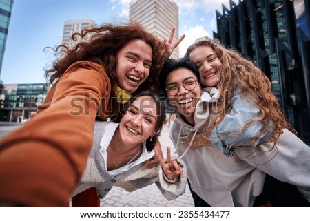Group of multiracial young people having fun taking a selfie in the city with a smartphone. Happy friends hugging and looking at the camera. On vacation from University.