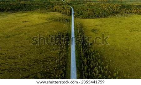 Aerial view of a Finnish road crossing a marshland on a summer evening