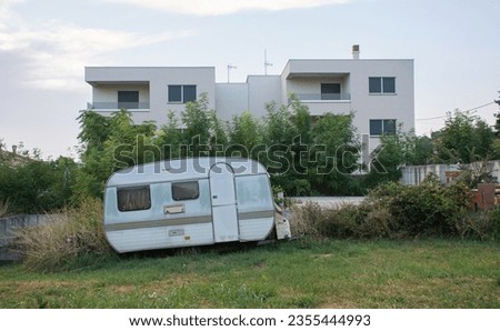 Vintage abandoned old trailer in front of a modern expensive house. Duality of modern world in a photo. Rich vs poor. Medulin, Croatia, Europe.