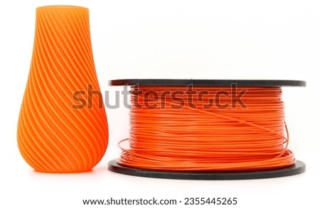 Orange vase and filament for 3d printing, isolated on white background, 3D Printer Filament, TPU Filament, horizontal view, macro Royalty-Free Stock Photo #2355445265