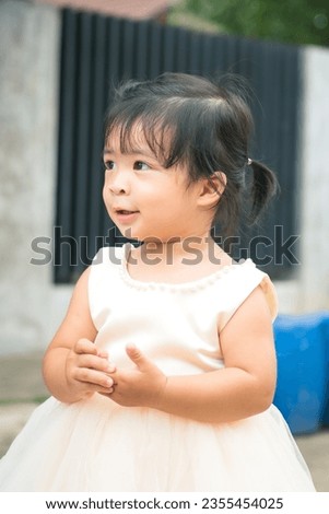 A little girl is white dress for attended the wedding event in cute action. Girl portrait photo, face focus.