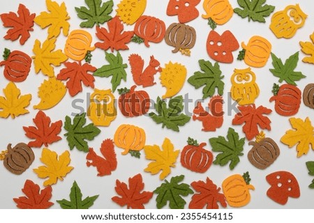 funny multi-colored felt details in the form of pumpkins, autumn maple leaves, owls, hedgehogs and squirrels are laid out on a white background. Halloween concept.