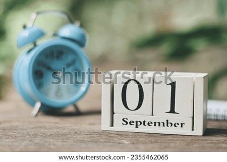 close up wooden calendar block, notebook and blue alarm clock on wood table, 01 September text, planning and manage time to success business concept