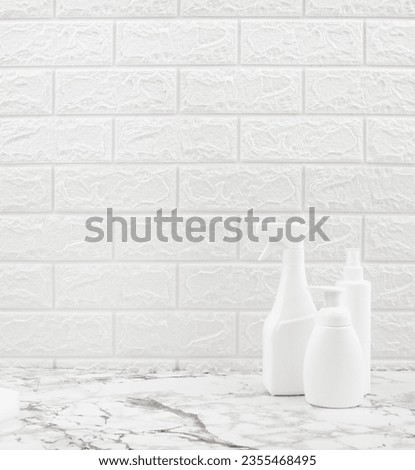 Cleaning product white bottles on marble table and with white tiles wall. Cleaning concept and household product background.