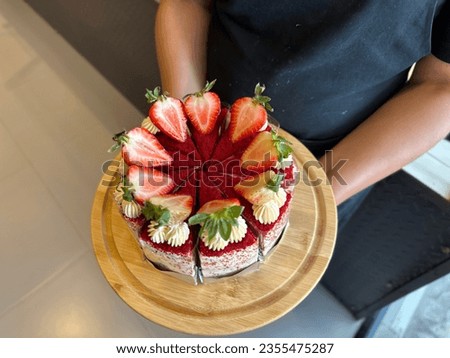 Woman holding plate with delicious Strawberry cream cheese cake. 
cheesecake on a wooden plate. Fresh  Strawberry topping with cream and thyme leaves. Bakery picture free space for text.