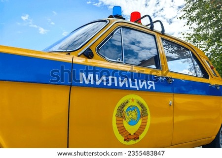 Patrol car Volga times of the USSR, Yellow and blue coloring, the coat of arms of the USSR and the inscription "proletarians of all countries unite", the inscription "Police" in Russian language. Royalty-Free Stock Photo #2355483847