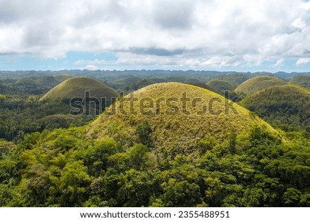 Amazingly shaped Chocolate hills on sunny day on Bohol island, Philippines. Dramatic cloudy sky on a sunny day, copy space for text