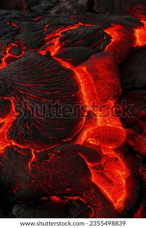 Experience the raw power of nature with this stunning image of molten lava flowing from a lava rock on the Big Island of Hawaii. The fiery colors and the rugged terrain make this image a must-have. Royalty-Free Stock Photo #2355498839