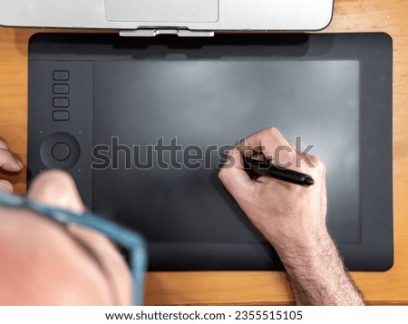 Man drawing with digital pen on graphic tablet