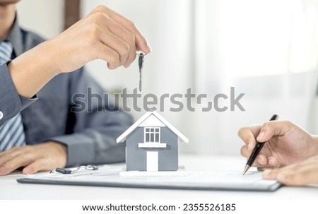Real estate agent broker hand over the house key to the new owner after completing the signing according to agreement renting a house and buy house insurance officially completed.