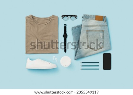 Personal accesories and menswear flat lay on blue background.