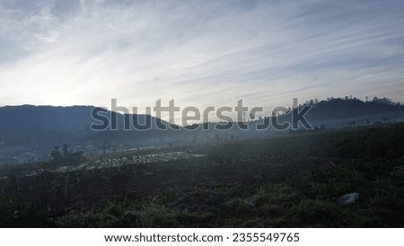 The Dieng landscape bathes in the early morning's enchanting mist, weaving an ethereal tapestry of wonder and intrigue. Royalty-Free Stock Photo #2355549765