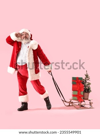 Santa Claus pulling sleigh with Christmas gifts on pink background