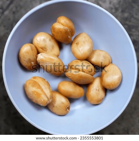 a photography of a bowl of peeled potatoes on a table, french loafs in a bowl on a table with a knife.